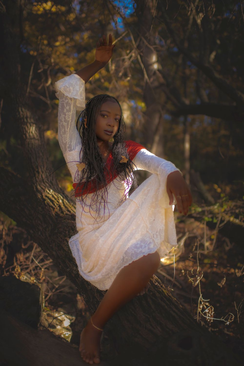 Artistic portrait showing graceful pose in white dress amid forest shadows.