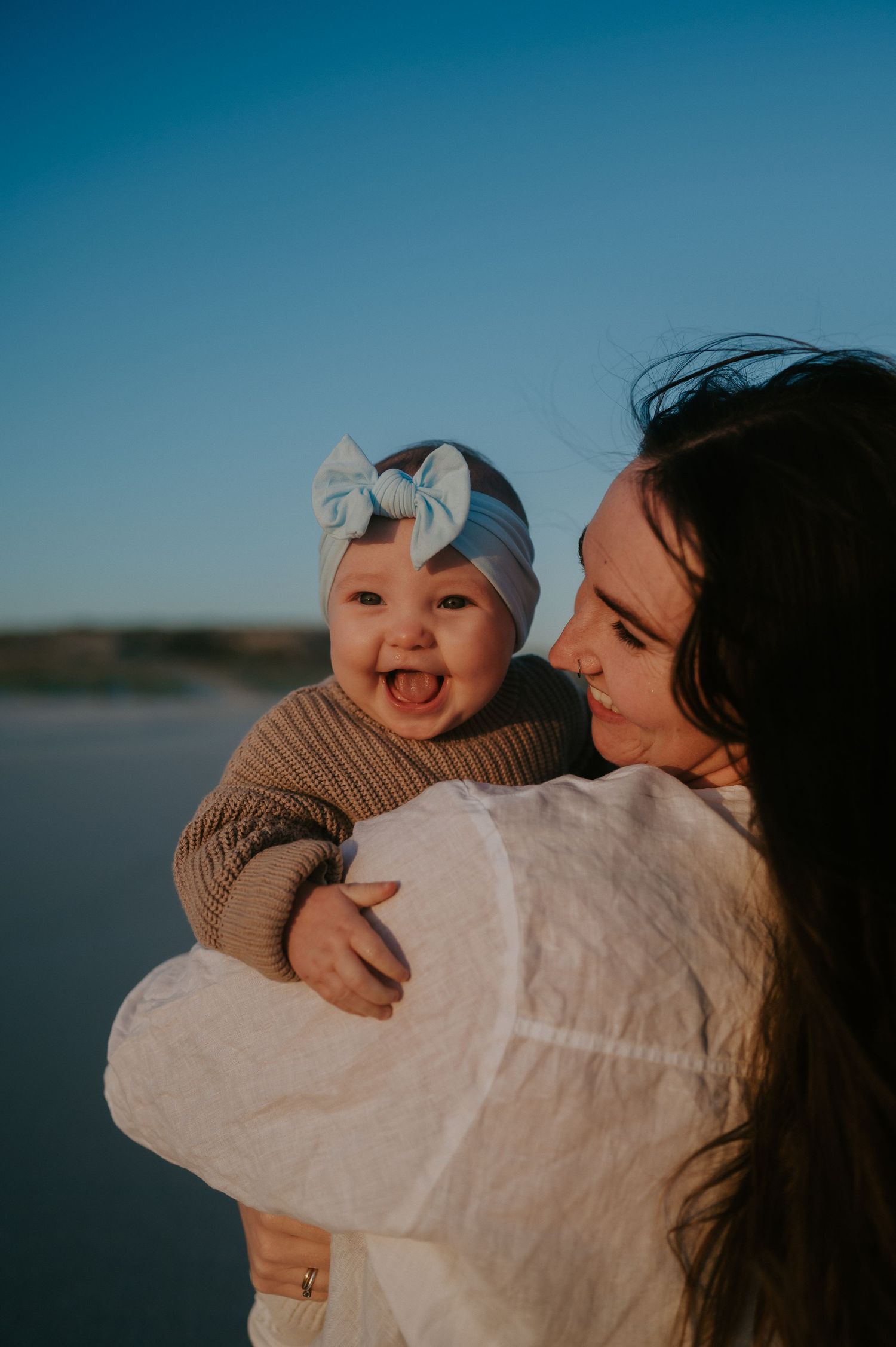 Smiling baby, held by her mum on the beach - Bremer Bay