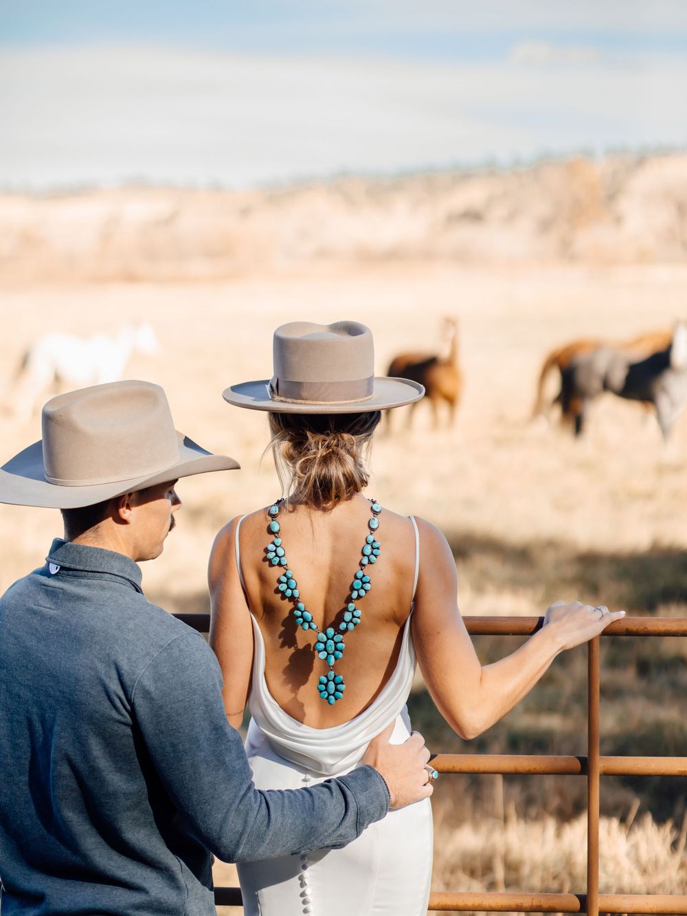 Couple in western attire viewing wildlife from observation deck with turquoise jewelry details.