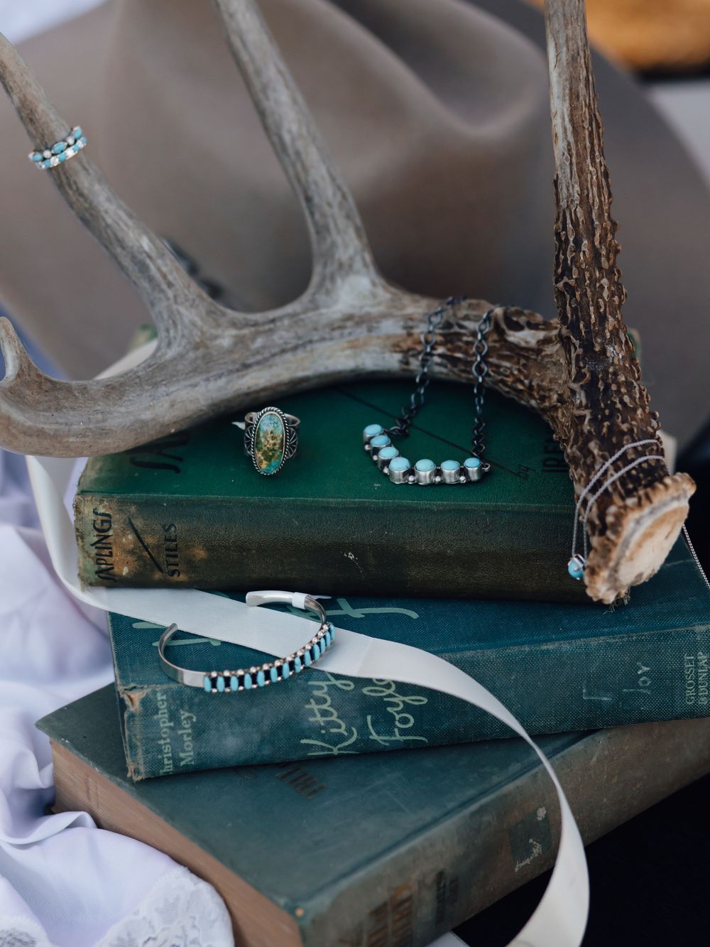 Vintage books with antler decor displaying turquoise jewelry pieces.