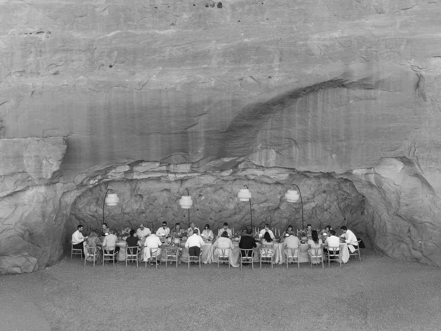 Wedding reception at ULUM Moab with guests dining beneath a sandstone rock overhang in the Utah desert