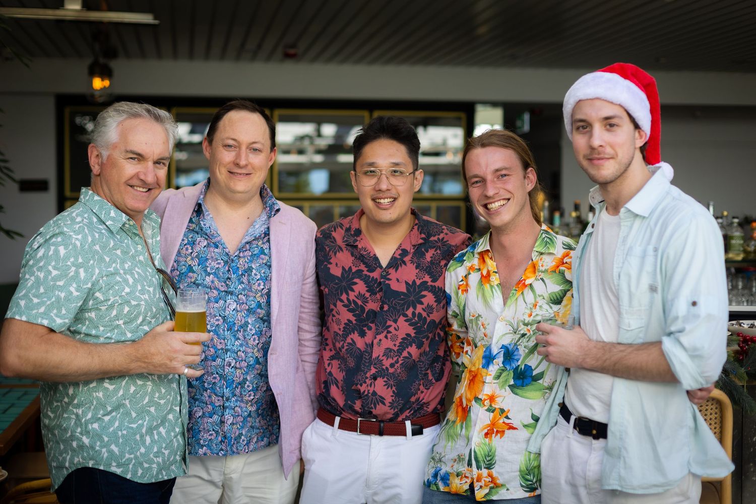Group of work friends in colourful shirts pose together at Christmas Party.