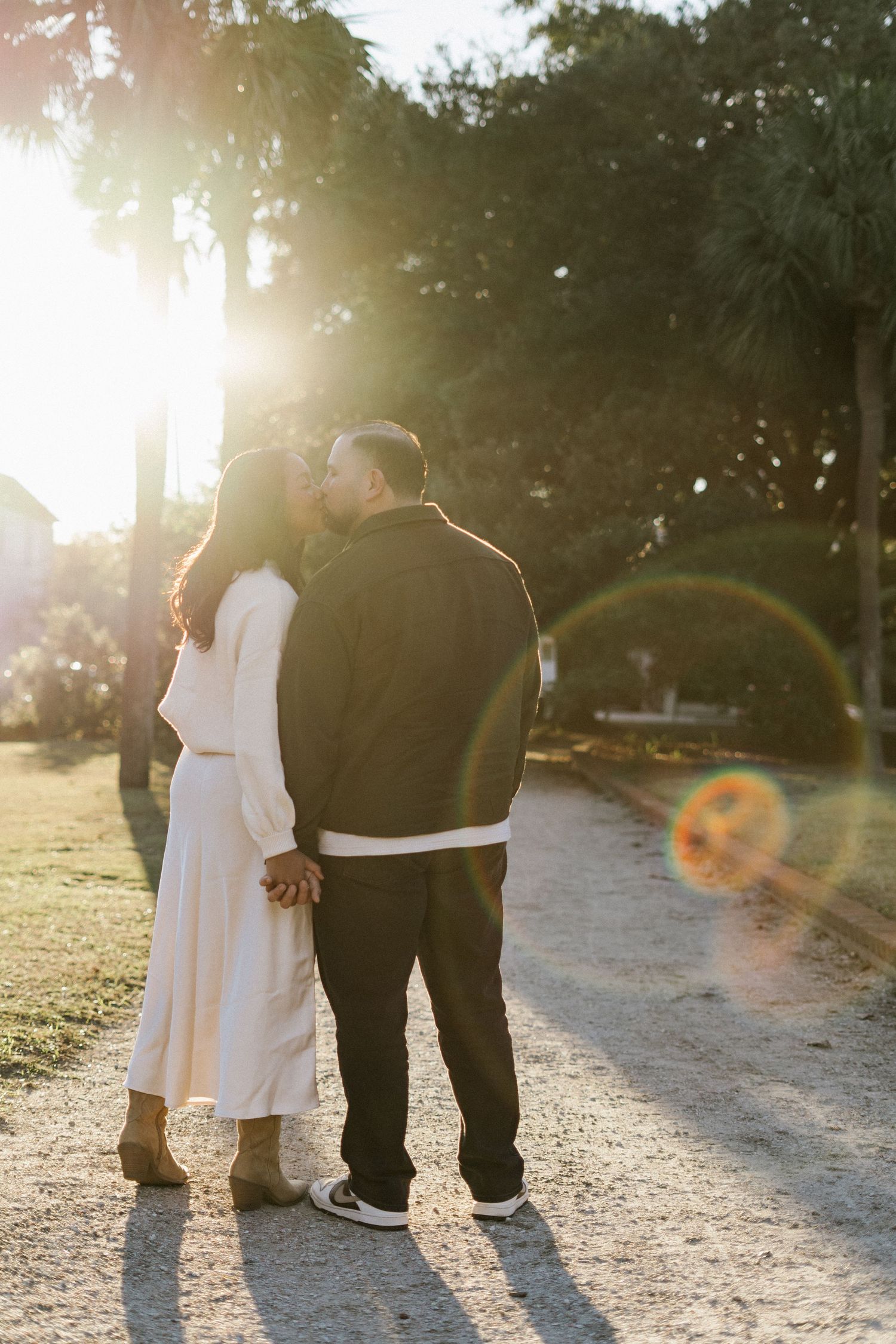 A couple in formal attire share a romantic moment on white marble steps outside an elegant building with classical columns.