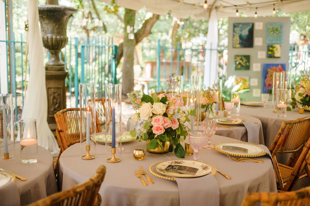 Rustic outdoor reception venue with string lights and white table settings under a tent.