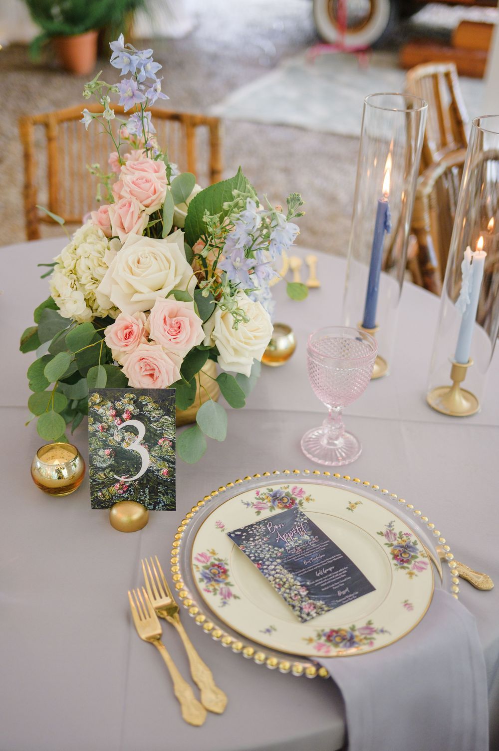 Romantic wedding table decor with pink and white floral centerpieces, gold cutlery, and gray linens.