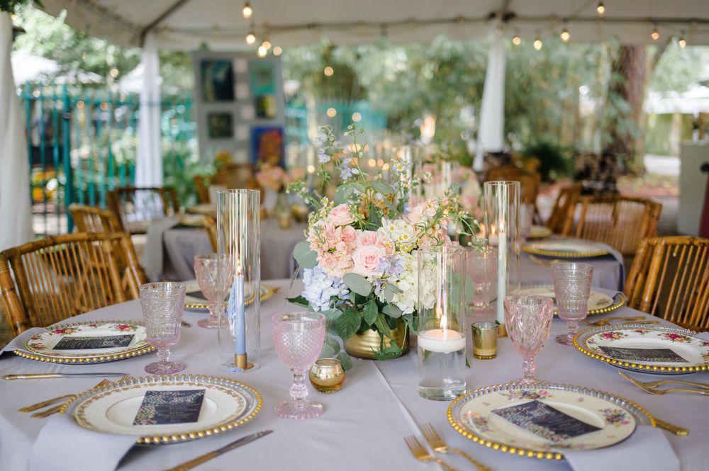 Wedding reception tables with bamboo chairs, white linens, and delicate floral arrangements.