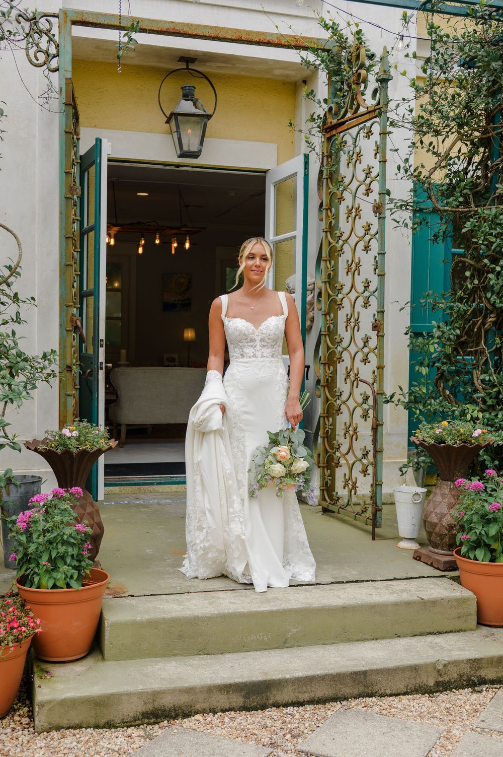 Charming white building exterior with green shutters and potted plants along the entrance.