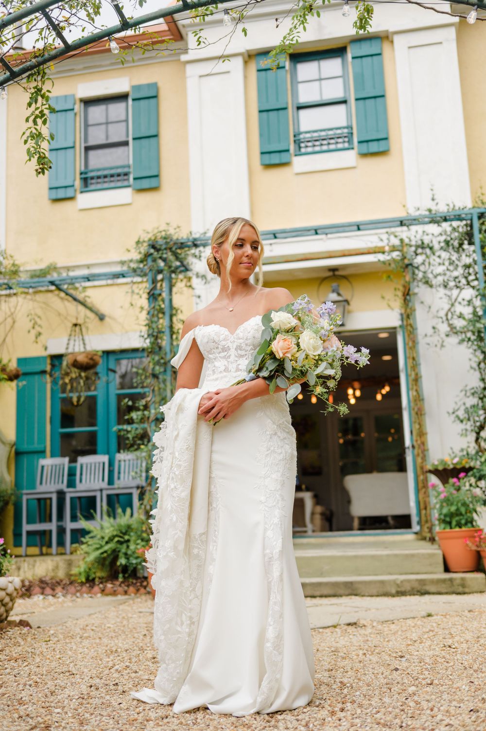 Beautiful wedding dress details shown against the backdrop of a charming French country house with teal shutters.