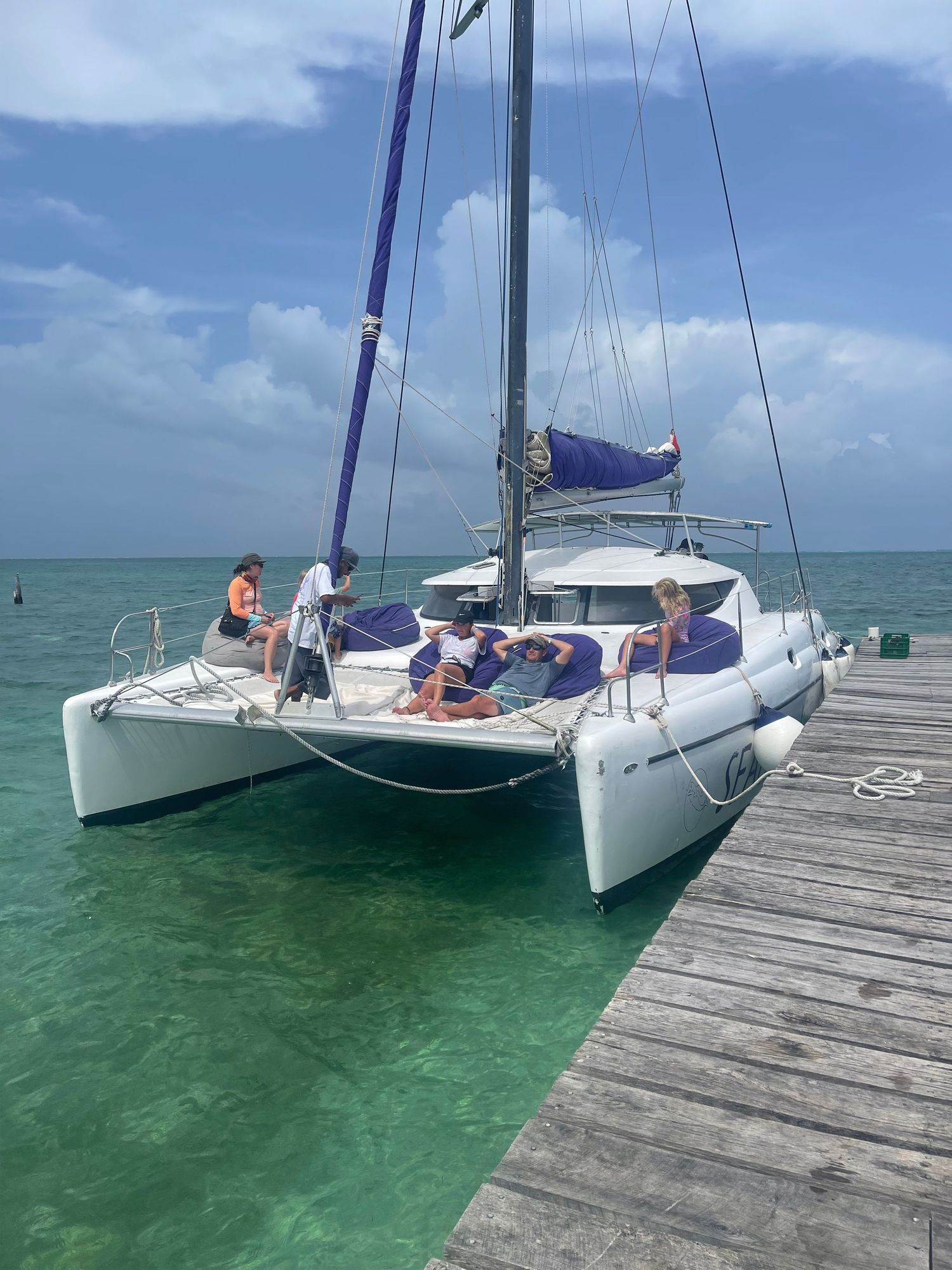 Catamaran sailboat docked at wooden pier in crystal clear Caribbean waters.