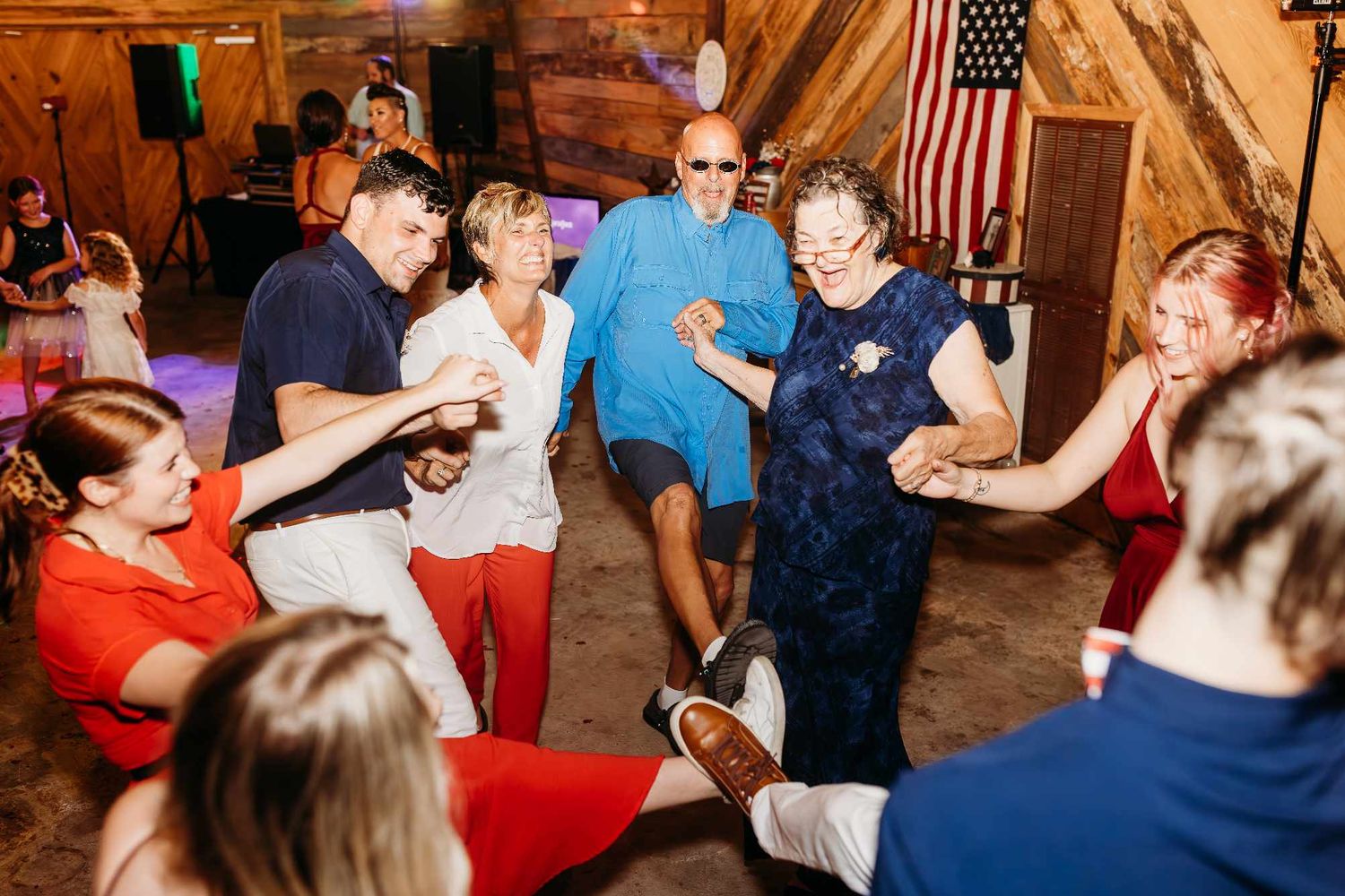 Wedding reception guests dancing and celebrating in a rustic indoor venue.