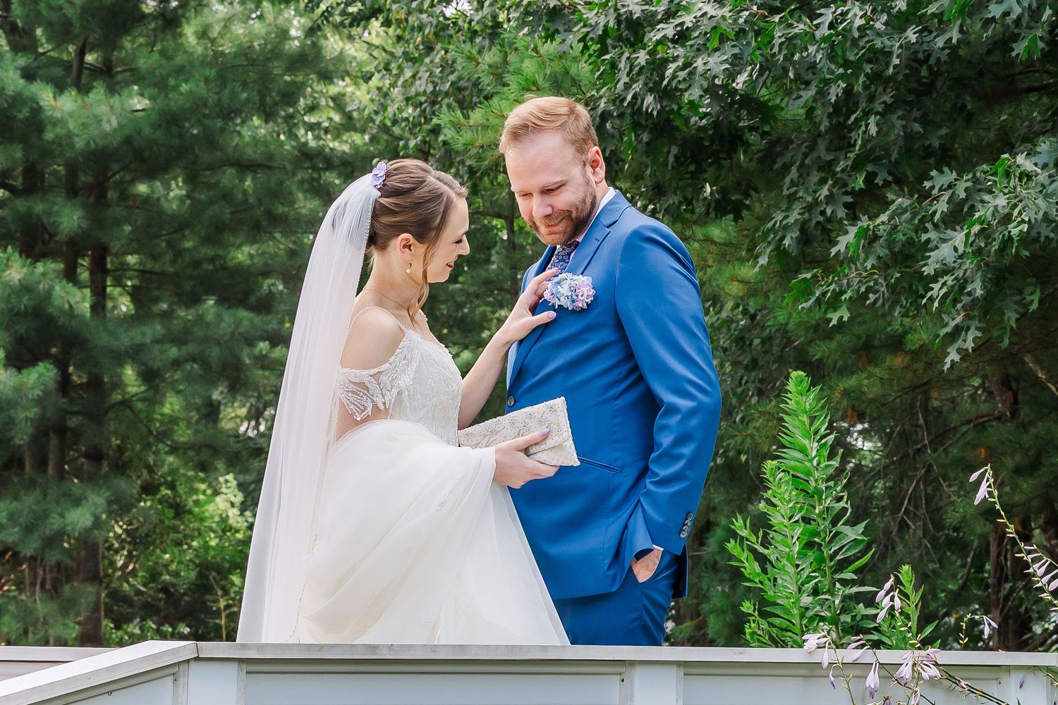 A couple shares an intimate moment during their outdoor wedding ceremony against a backdrop of lush greenery.