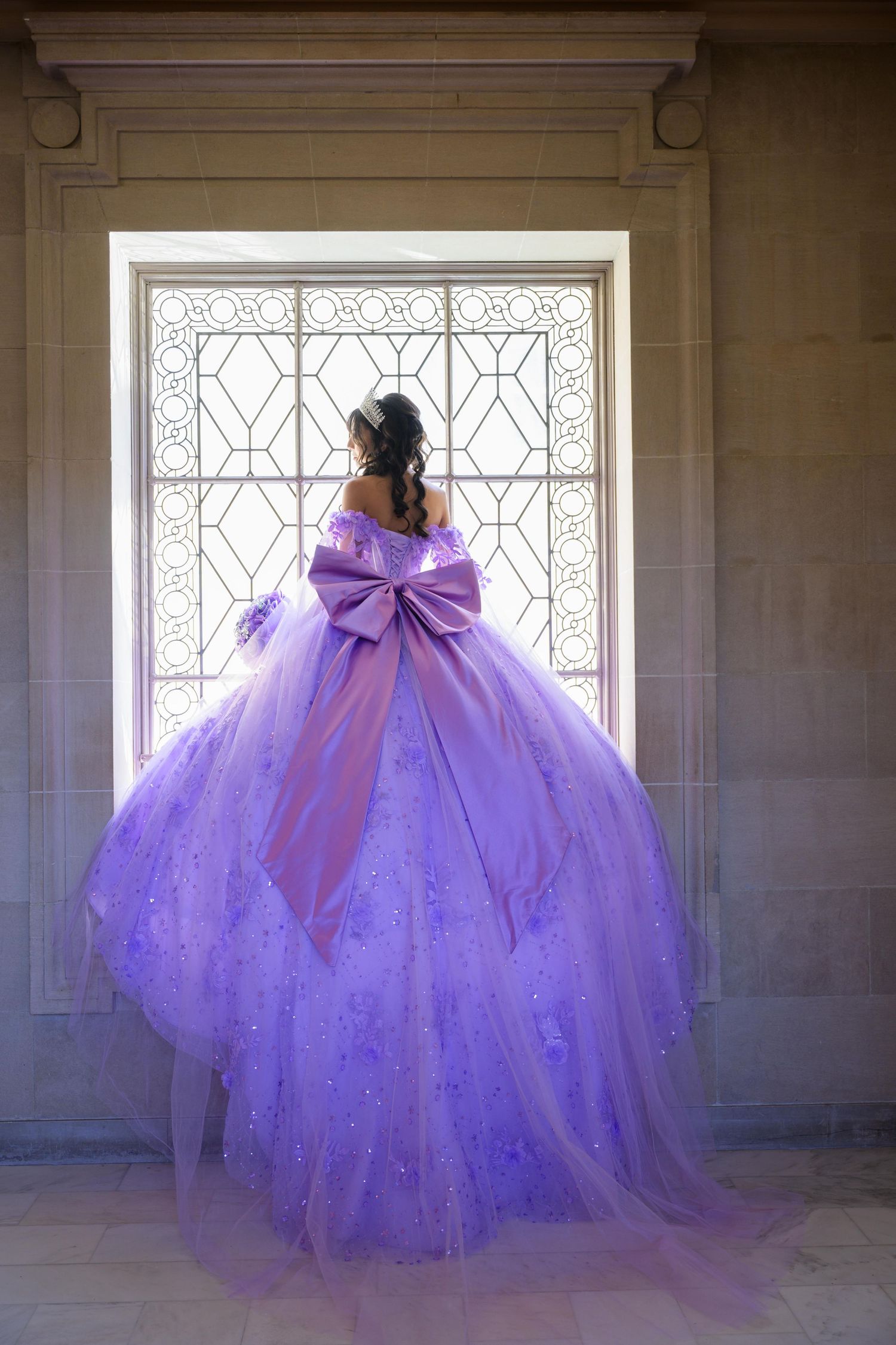 A flowing purple ballgown with sparkles and a dramatic bow photographed in sequence against ornate windows and stone walls.