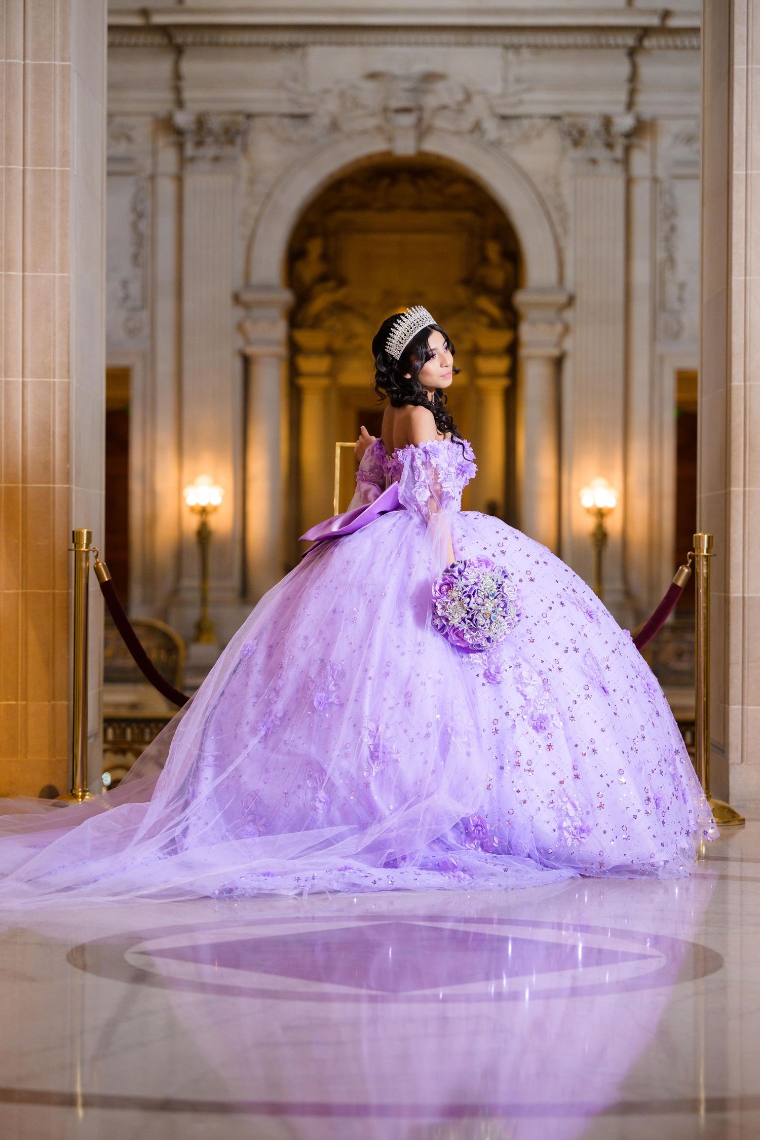 Lavender ball gown with sparkling details and long train photographed in an elegant classical palace hallway.