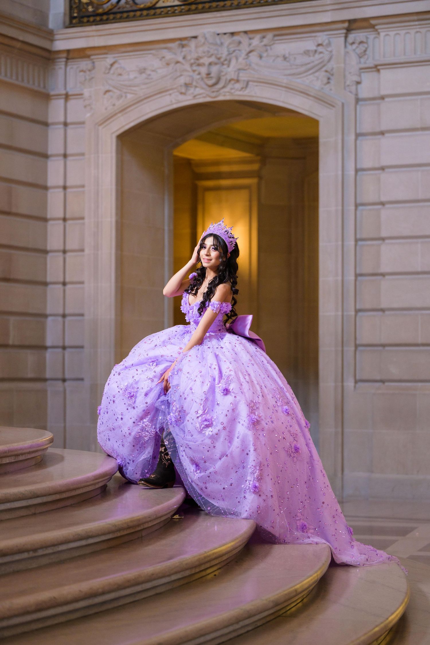A lavish purple quinceañera ball gown cascades down elegant marble stairs in an ornate classical interior hallway.