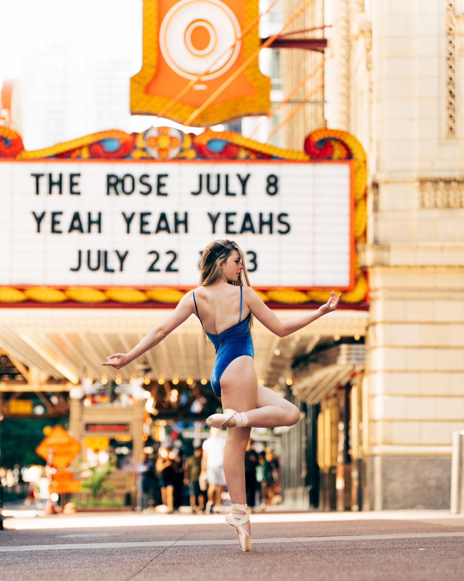 chicago dance photographer Ballerina Scarlett stretching in black skirt with chicago theater sign in the background
