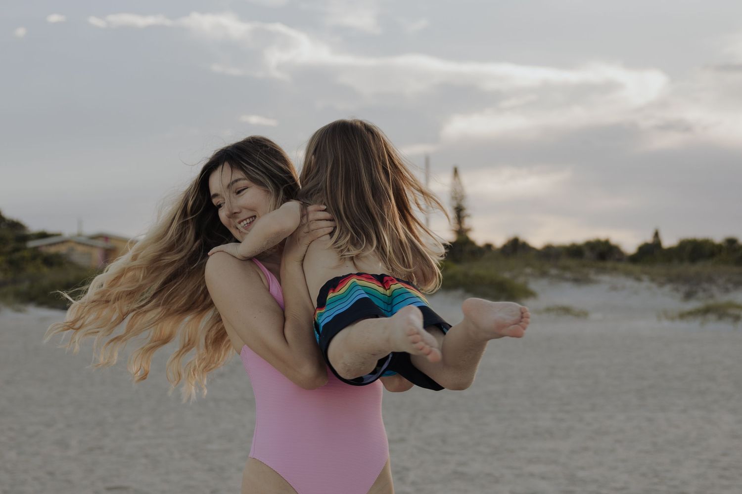 Playful beach photoshoot with couple dancing in casual attire.