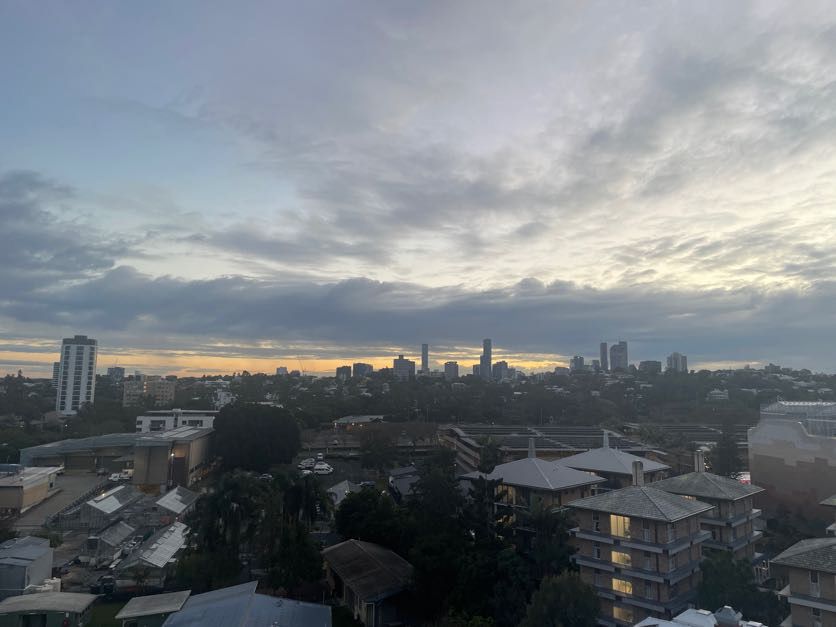 Panoramic cityscape view of Brisbane at sunset with cloudy skies.