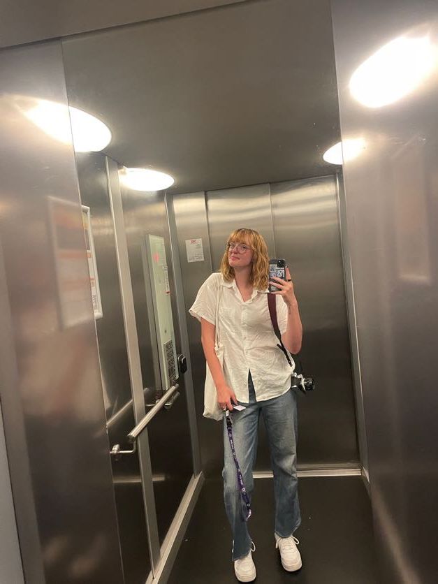 Mirror selfie taken in a modern elevator with metallic walls.
