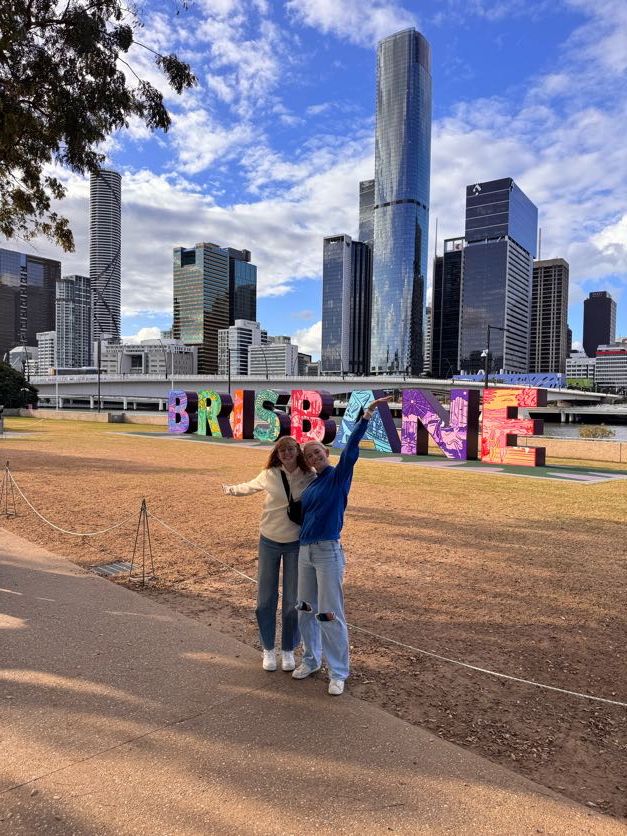 Colorful Brisbane sign with city skyline and tall buildings in the background.