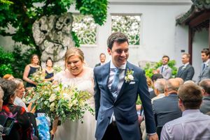 A joyful wedding celebration in a garden setting with guests looking on.
