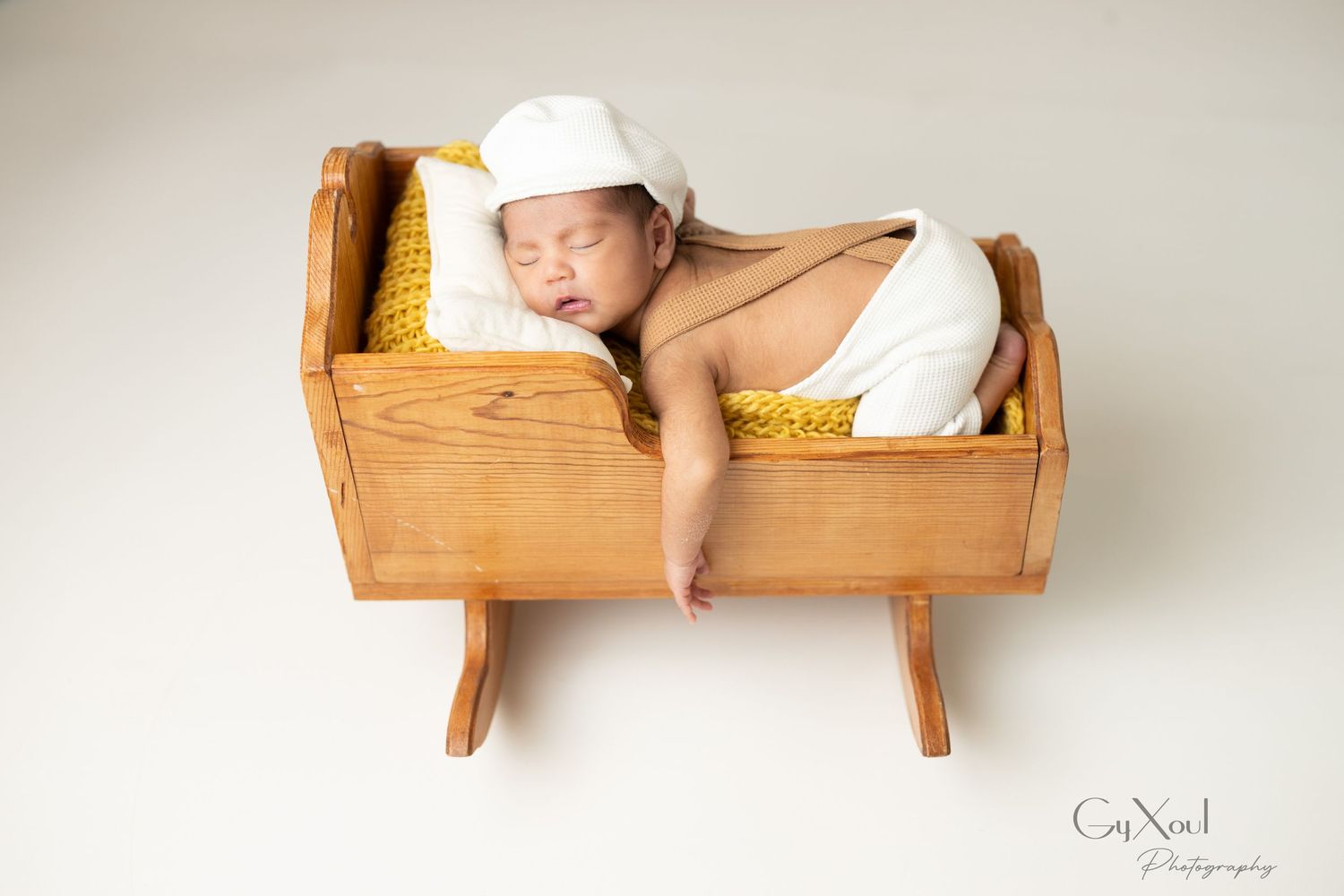 Baby's legs peeking out from a rustic wooden crib in a soft, natural light setting with white bedding details.