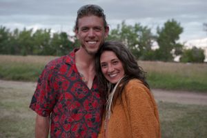 A couple smiling together outdoors on a cloudy day.