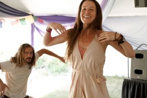 Two people dancing joyfully under a decorated tent at an outdoor event.