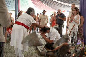 People gather around during a ceremonial moment under a decorated festival tent.