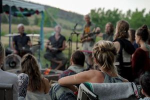 A band performs on stage at an outdoor venue with rolling hills in the background.