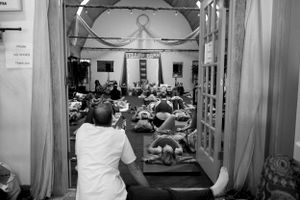 View through doorway of people seated in rows during an indoor gathering.