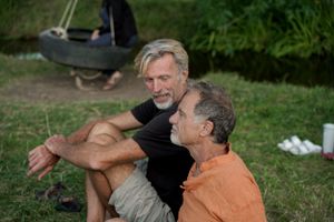 Two people sit together outdoors having an animated conversation in a casual outdoor setting.