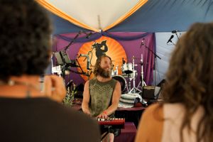 A performance setup under a tent with colorful fabric decorations and musical instruments.