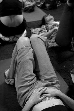 Black and white image of people lying on yoga mats during a wellness session.