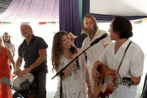 A group performs music together during an indoor celebration with fabric-draped ceilings.