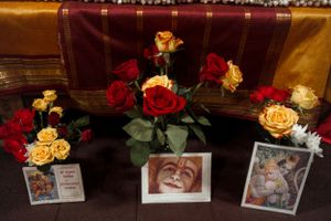 Red and yellow roses arranged in vases with framed photographs on display.