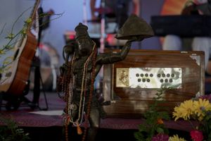 Decorative statue and vintage equipment displayed on a stage with flowers.