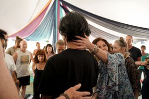 A group gathers under a decorated tent with colorful draping fabric during an event.