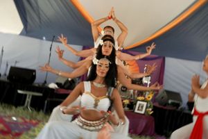 Performers in white outfits striking graceful poses during an outdoor dance performance.