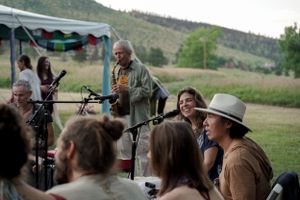 Musicians perform for a crowd at an outdoor venue with mountains visible in the distance.