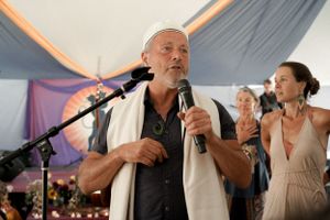 A musical performance takes place under a tent with purple and orange draped fabric.