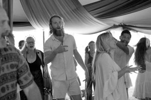 People dancing and celebrating at a monochrome-captured festival under draped fabric decor.
