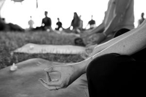 Black and white image of meditation participants sitting in peaceful outdoor setting.