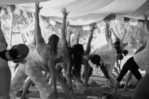 A black and white photo captures people stretching in unison during a yoga class.
