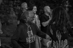 A group of people enjoying a performance or event outdoors in black and white.