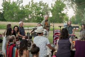 Musicians performing for a seated audience at an outdoor summer festival.