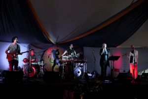 A band performs on a dimly lit stage with dramatic lighting and backdrop.