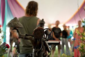Close-up of musical equipment and decorations under a draped tent with people in background.