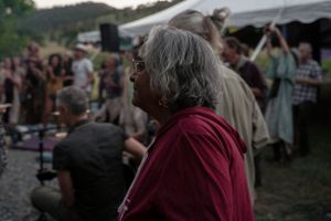 An outdoor festival crowd watches performers as the sun sets.