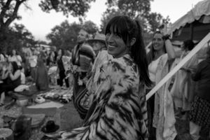 Someone wearing a tie-dye pattern garment dances at an outdoor gathering.