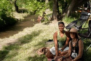 People enjoying a summer day by a creek with sun hats and outdoor gear.